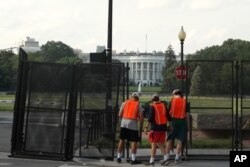 Workers remove a security fence, June 10, 2020, near the White House in Washington.