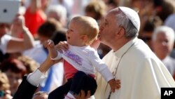 El papa Francisco besa a un niño en la Plaza de San Pedro en el Vaticano.