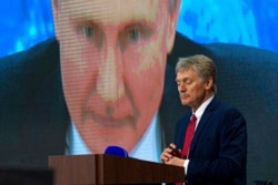 FILE - Russian President Vladimir Putin speaks via video call, as Kremlin spokesman Dmitry Peskov looks on, during a news conference in Moscow, Russia, Dec. 17, 2020.