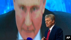 Juru bicara Kremlin Dmitry Peskov dengan latar belakang Presiden Rusia Vladimir Putin yang berbicara melalui panggilan video, saat konferensi pers di Moskow, Rusia, 17 Desember 2020. (Foto: AP)