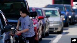 Un cliente bombea gasolina en Costco, mientras otros esperan en la fila, en Charlotte, Carolina del Norte, el 11 de mayo de 2021.