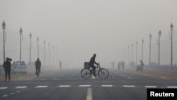 A newspaper vendor rides his bicycle on a smoggy morning in New Delhi, India, Dec. 1, 2015.