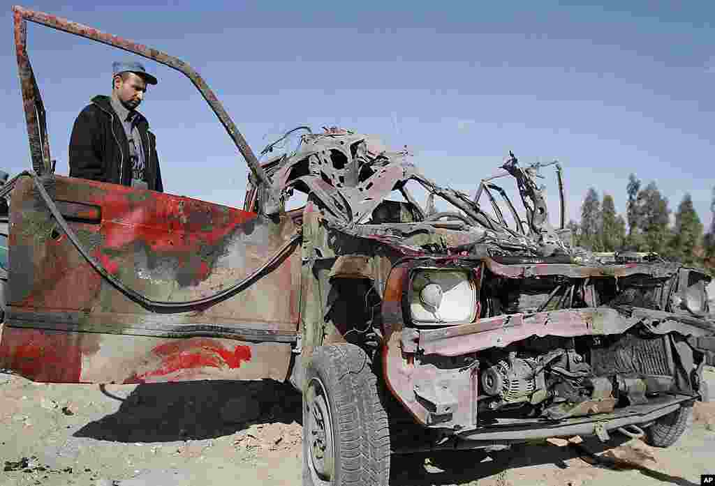 An Afghan police officer inspects a vehicle damaged at the scene of a suicide attack at the gate of an airport in Jalalabad, Nangarhar province on February 27, 2012. (AP)