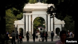 People walk near the gate of Tsinghua University in Beijing, China, July 27, 2016.