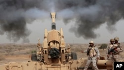 FILE - In this April 20, 2015 file photo, Saudi soldiers fire artillery toward three armed vehicles approaching the Saudi border with Yemen in Jazan, Saudi Arabia.