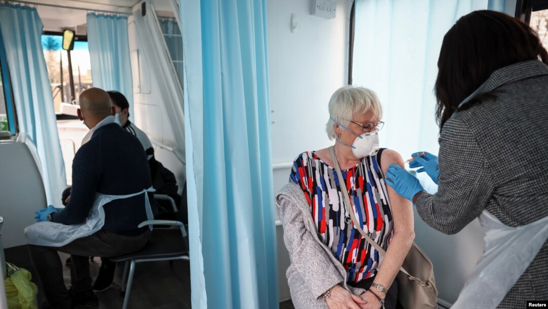 A woman receives a dose of the Oxford-AstraZeneca COVID-19 vaccine inside a mobile vaccination center for the COVID-19, in Thamesmead, London, Feb. 14, 2021. 