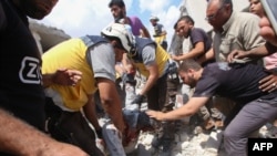 Syrian rescuers and civilians pull a man from the rubble of a building following an airstrike by regime forces in Maar Shurin on the outskirts of Maaret al-Numan in northwest Syria, July 16, 2019. 