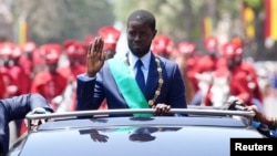 Senegal's newly-elected President Bassirou Diomaye Faye waves to supporters from a car after taking an oath of office as president during the inauguration ceremony in Dakar