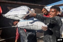 FILE —Workers unload bags of humanitarian aid that entered Gaza by truck through the Kerem Shalom (Karm Abu Salem) border crossing in the southern part of the Palestinian territory on February 17, 2024, in Rafah on the southern Gaza Strip.