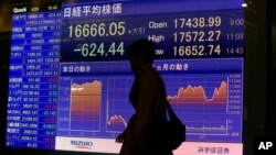 A man walks by an electronic stock indicator of a securities firm in Tokyo, April 28, 2016. 