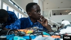 Aboubacar Savage, 14, from Gambia looks at a computer at the 2017 Pan-African Robotics Competition in Dakar, Senegal, May 19, 2017. (R. Shryock/VOA)