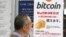 FILE - A man walks past a poster of bitcoin displayed at a retail store in Tokyo, Jan. 19, 2018.