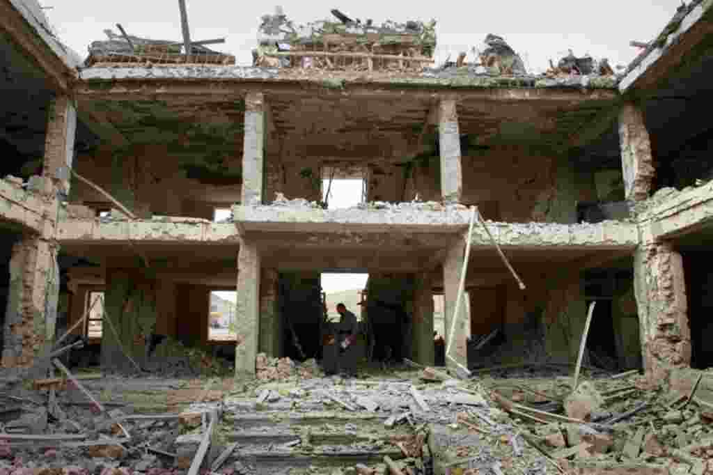 April 14: An Afghan police official investigates a damaged building at the scene of a suicide car bomb explosion on the outskirts of Kabul, Afghanistan. (AP)