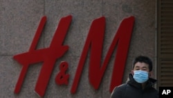 A man wearing a face mask walks by a Swedish fashion brand H&M store outlet in Beijing, March 25, 2021. 