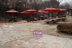 FILE - A part of park is taped off with a sign which reads "Access restrictions to prevent the spread of COVID-19" for the social distancing measures and a precaution against the coronavirus at a park in Seoul, Dec. 23, 2020.