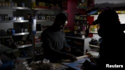 A shopkeeper counts change by the light of a battery-powered lamp during a load-shedding electricity blackout in Cape Town, South Africa, April 15, 2015. Electric utility Eskom has continued power cuts into January 2023.