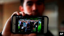 FILE - Amos Cao, son of detained Chinese Rev. John Sanqiang Cao, holds a family photo showing his father (R) in Ann Arbor, Mich., April 10, 2018.