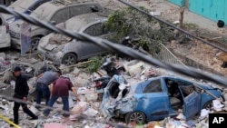 Warga memeriksa lokasi serangan udara Israel di pinggiran selatan Beirut, Selasa, 24 September 2024. (Hassan Ammar/AP)