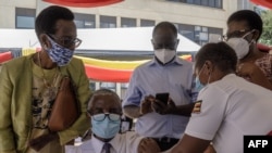 FILE - An Ugandan doctor (C-L) receives the first injection of the Oxford AstraZeneca COVID-19 vaccine at Mulago referral hospital in Kampala, on the first day of a vaccination campaign on March 10, 2021. 