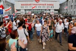 Workers of the Minsk Tractor Works Plant leave after their work shift as activists with old Belarusian national flags greet them in Minsk, Belarus, Aug. 18, 2020.