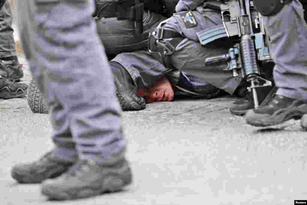 Israeli policemen detain a Palestinian protestor during scuffles outside the compound housing al-Aqsa Mosque in Jerusalem&#39;s Old City. Israeli police closed the entrances to Jerusalem&#39;s most sensitive holy site after Palestinian suspects threw a firebomb at a police station.