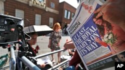 A news cameraman reads a newspaper across from St. Mary's Hospital's exclusive Lindo Wing in London, July 22, 2013. 