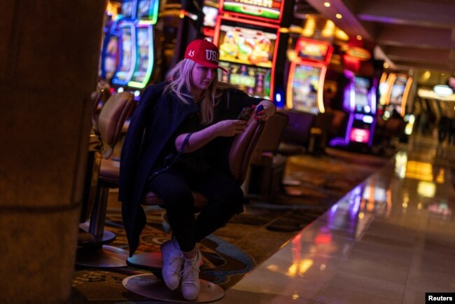 Una partidaria del candidato presidencial republicano Donald Trump mira su teléfono junto a las máquinas tragamonedas en Treasure Island Resort & Casino después de asistir a una fiesta nocturna del caucus de Nevada en las Vegas, Nevada, EEUU, el 8 de febrero de 2024.