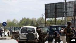 FILE - Afghan security forces inspect the site of a bomb explosion near a damaged vehicle in Kabul, Afghanistan,, April 27, 2020. 