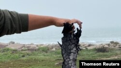 A spectator holds a piece of debris which was blown 5 miles from the site where SpaceX test rocket SN11 exploded upon landing, in Boca Chica, March 30, 2021.