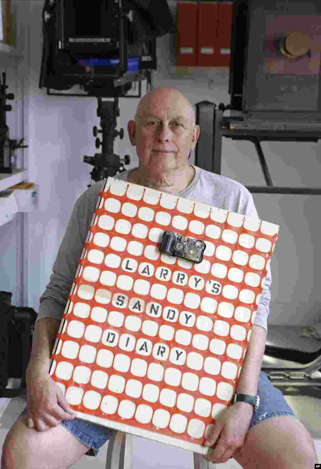 Larry Racioppo, pensiunan fotografer dari Departemen Perumahan dan Pelestarian New York, memperlihatkan buku harian dan album foto miliknya di rumahnya di pelabuhan Belle, Queens, New York. (AP/Kathy Willens)