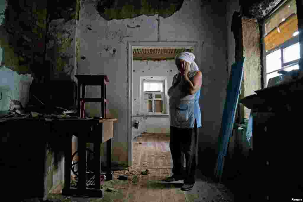 Local resident Katerina Izvekova, 77, shows her house damaged during a military conflict between militants of the self-proclaimed Donetsk People&#39;s Republic and the Ukrainian armed forces in the rebel-controlled village of Vesele in Donetsk region.