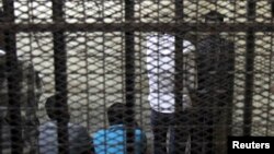 FILE - Defendants are seen standing behind bars in a Cairo court.