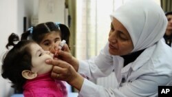 Ma'aikaciyar lafiya tana ba jaririya maganin rigakafin Polio a kasar Syria