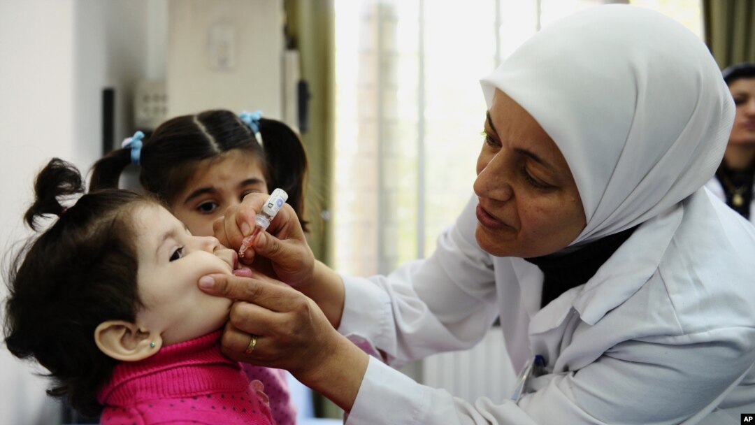 FILE - A health worker administers polio vaccine to a child as part of a UNICEF-supported vaccination campaign at the Abou Dhar Al Ghifari Primary Health Care Center in Damascus, Syria, Oct. 29, 2013.