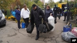 People carry their possessions after being evacuated from Kupiansk, at a distribution center for internally displaced persons, in Kharkiv, Ukraine, Oct. 17, 2024.