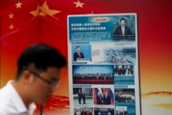 FILE - A man walks by a government billboard promoting Chinese President Xi Jinping's signature "Belt and Road" initiative, outside a subway station in Beijing, Aug. 28, 2018.