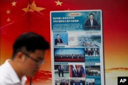 FILE - A man walks by a government billboard promoting Chinese President Xi Jinping's signature Belt and Road Initiative, outside a subway station in Beijing, China, Aug. 28, 2018.