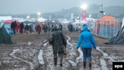 Quelques personnes marchent dans la boue après la foudre qui est tombée lors du festival "Rock am Ring" à Mendig, Allemagne, 3 juin 2016. epa / THOMAS FREY