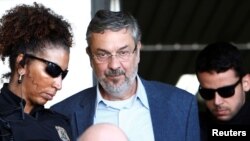 FILE - Antonio Palocci, center, former finance minister, is escorted by federal police officers as he leaves the Institute of Forensic Science in Curitiba, Brazil, Sept. 26, 2016. 