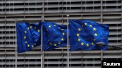 FILE - European Union flags flutter outside the EU Commission headquarters in Brussels, Belgium, May 5, 2021. 
