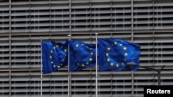 FILE - European Union flags flutter outside the EU Commission headquarters in Brussels, Belgium, May 5, 2021. 