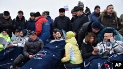 Astronot AS Scott Kelly (kanan, sedang menelpon) dan kosmonot Rusia Mikhail Kornienko (kiri) sesaat setelah mendarat di Dzhezkazgan, Kazakhstan (2/3).