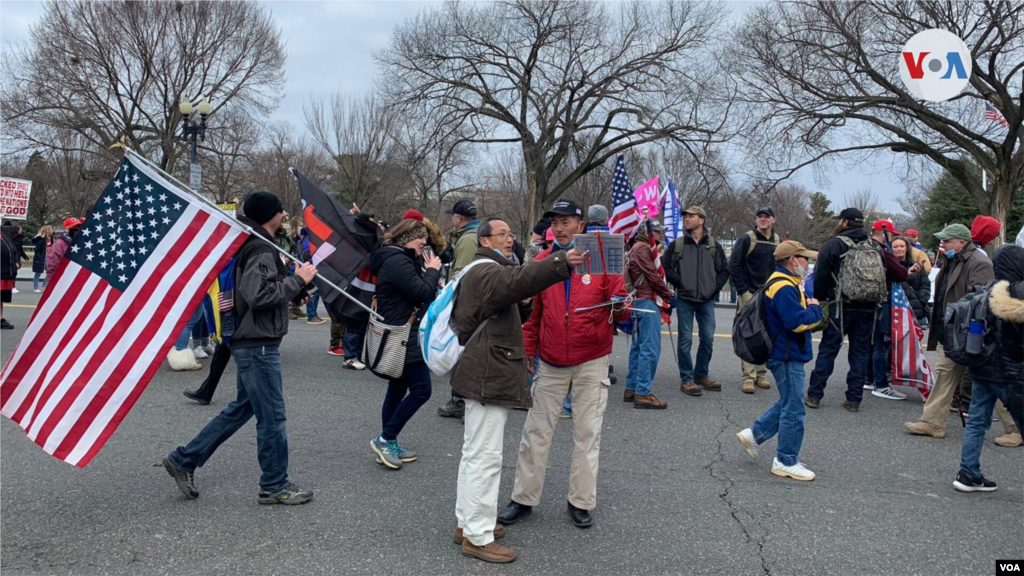 Simpatizantes de Trump caminan hacia la Casa Blanca con banderas y pancartas.