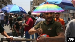 An Iraqi street vendor wears an umbrella-shaped hat to protect his head from the sun during a heat wave in the capital Baghdad, June 14, 2019.