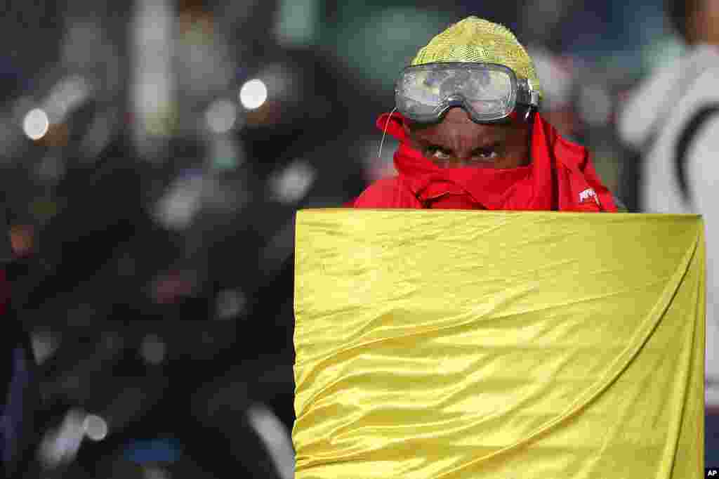 A demonstrator walks behind a homemade shield during an anti-government protest that blocks a bus terminal in Bogota, Colombia.