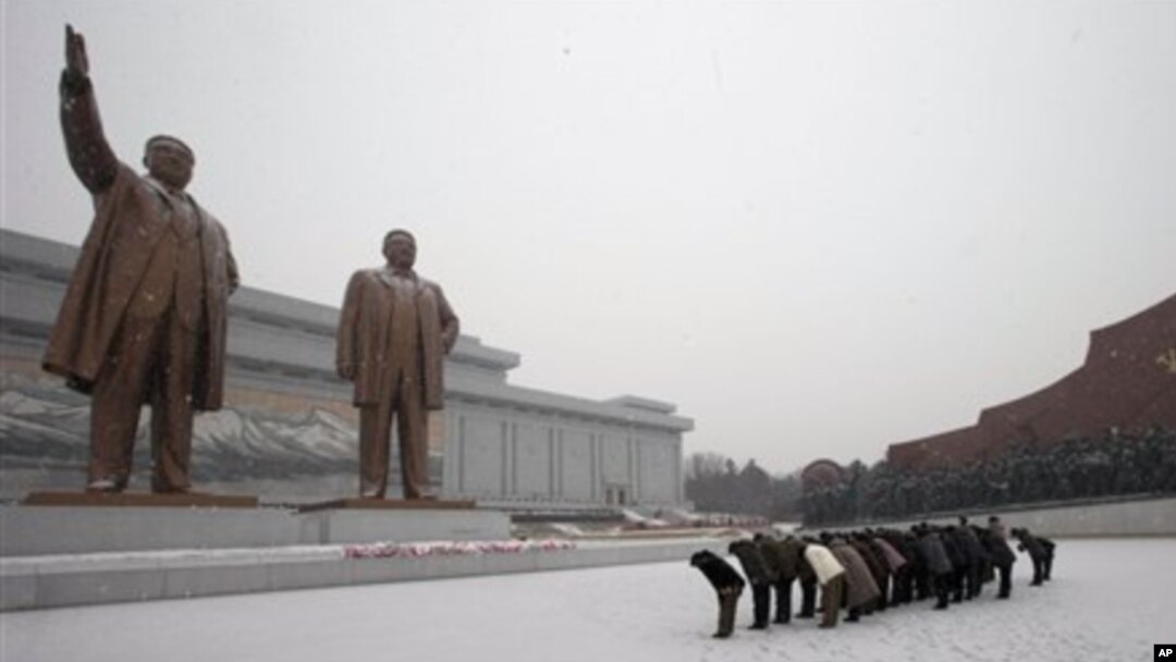 Warga Korea Utara memberi hormat kepada patung mendiang pemimpin Korea Utara, Kim Il-sung dan Kim Jong-il di Mansu Hill, saat salju menyelimuti Pyongyang, Korea Utara (21/12). Media setempat mengabarkan wisatawan Amerika, Bae Jun Ho ditahan di negara itu atas tuduhan melakukan tindak kejahatan.