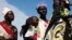 FILE - A woman carries a baby as she talks with other women talk at a food distribution center in Minkaman, Lakes State, South Sudan, June 27, 2014. Activists are calling on the leaders of the Transitional Government of National Unity to include more women in government roles.
