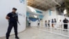 A police officer stands guard as people queue to cast their vote outside a polling station during a second round runoff of a presidential election in Tunis, Tunisia, Oct. 13, 2019. 