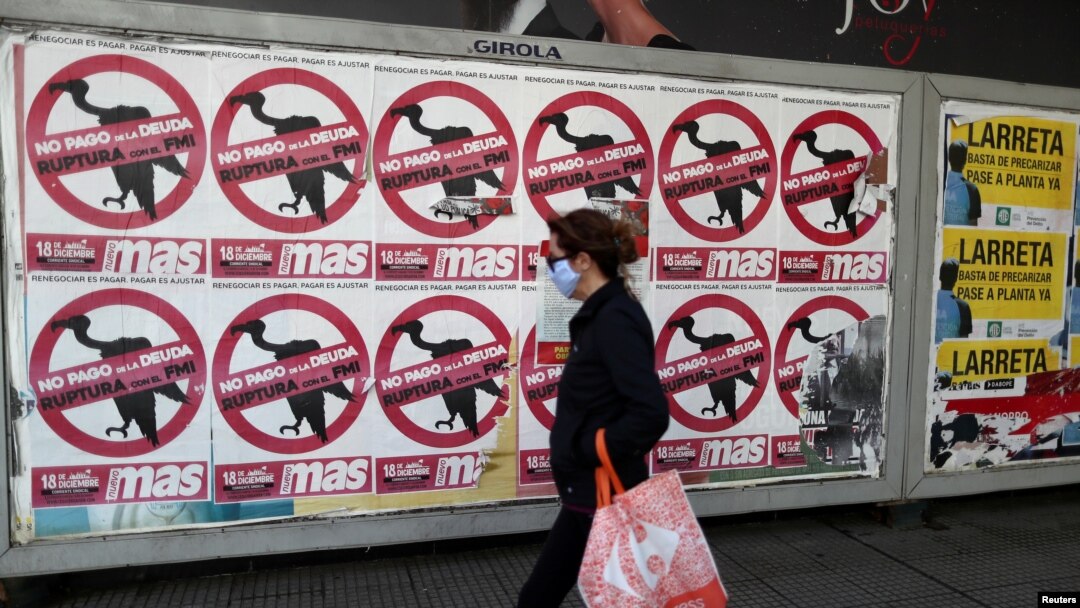 Seorang pejalan kali melewati poster yang bertuliskan "Jangan Bayarkan Utang. Keluar dari IMF" yang terpasang di jalanan kota Buenos Aires, Argentina, pada 27 Mei 2020. (Foto: Reuters/Agustin Marcarian)