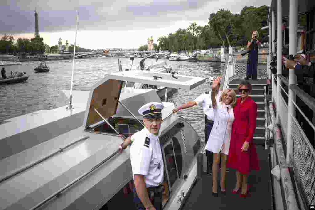 U.S. first lady Melania Trump, right, and Brigitte Macron, wife of French President Emmanuel Macron, wave after a boat trip down the River Seine in Paris.